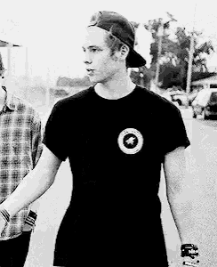 a man wearing a baseball cap and a black t-shirt is walking down the street .