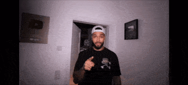 a man wearing a black shirt and a white hat is pointing at something