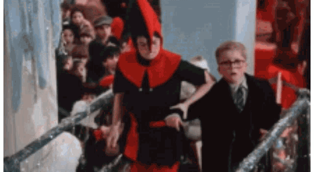 a man in a red and black costume is standing next to a boy in a black suit and tie .