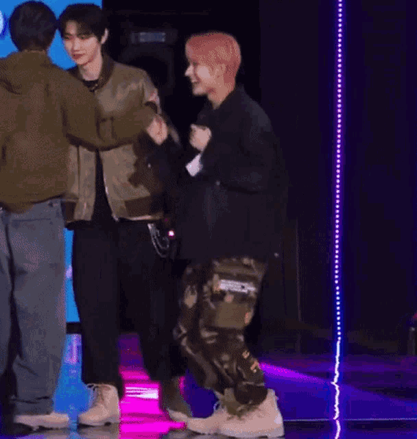 a group of young men are standing on a stage holding hands .