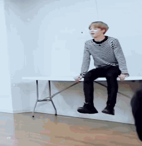 a man in a striped shirt sits on a white table