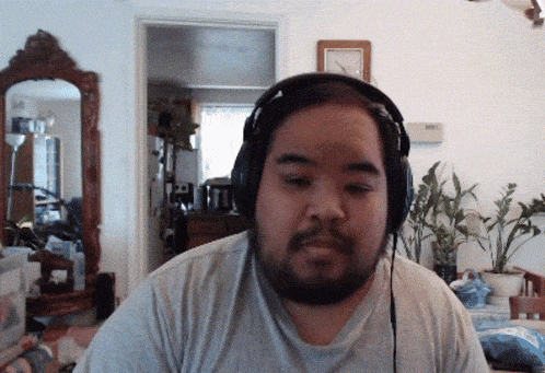 a man wearing headphones looks at the camera in front of a mirror
