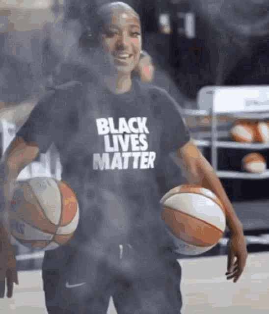 a woman wearing a black t-shirt that says black lives matter holds two basketballs