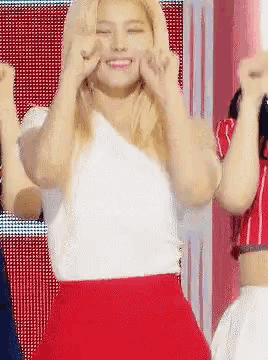 a blonde woman in a white top and red skirt is dancing