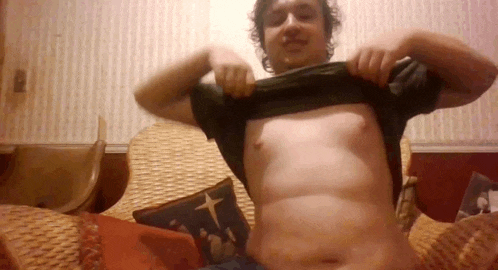 a man is sitting in a chair and taking off his shirt