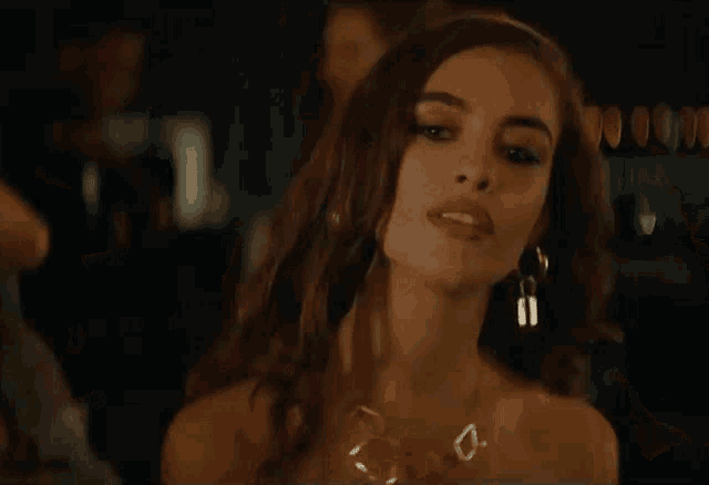 a woman in a strapless dress and earrings is standing in a crowd at a party .