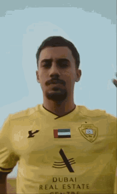 a man in a yellow dubai real estate centre shirt