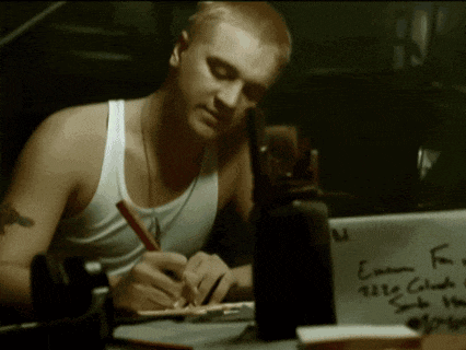 a man writing on a piece of paper that says eminem on it