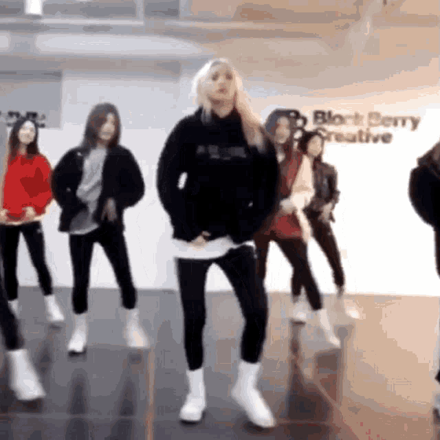 a group of women are dancing in front of a sign that says " blackberry creative "