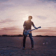 a man is playing an electric guitar in the desert at sunset ..