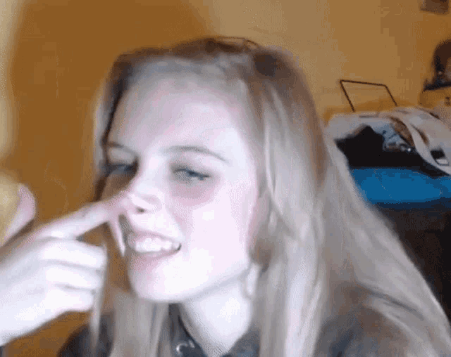 a woman with long blonde hair is holding her nose
