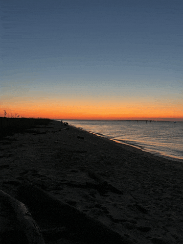 a sunset over a body of water with a silhouette of a person on the shore