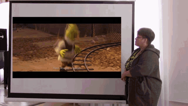 a woman is standing in front of a projector screen showing shrek