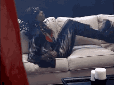 a man is laying on a white couch with his legs up