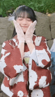 a woman wearing a red and white kimono and white gloves is smiling .