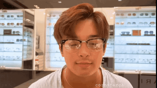 a man wearing glasses is standing in front of a display of glasses and a sign that says corner arch