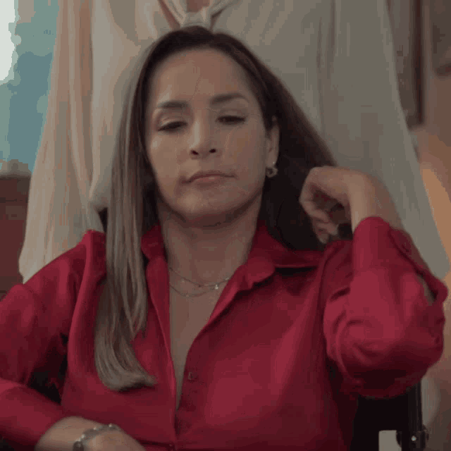 a woman wearing a red shirt is sitting in a chair