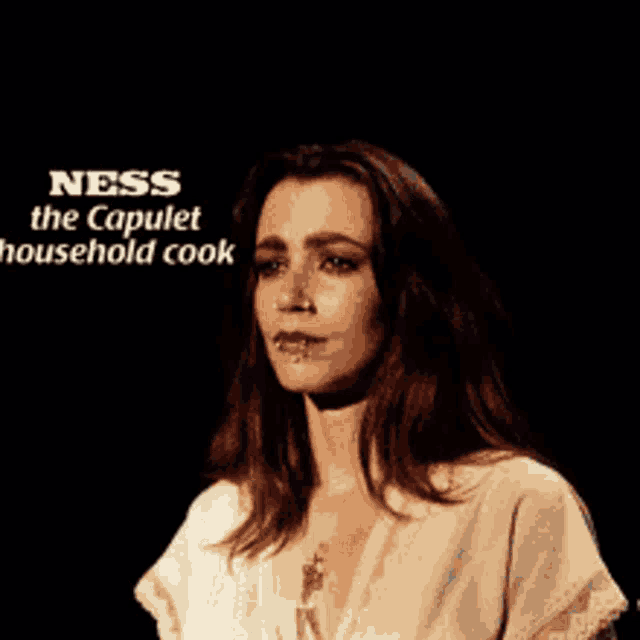 a woman stands in front of a sign that says ness the capulet household cook