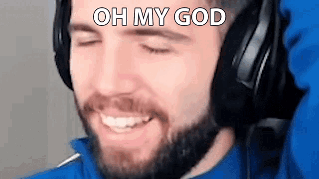 a man with a beard wearing headphones is smiling and making a funny face .