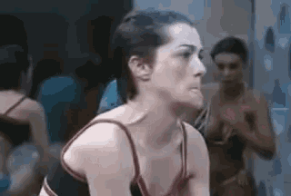 a woman in a red top is looking at herself in a mirror .
