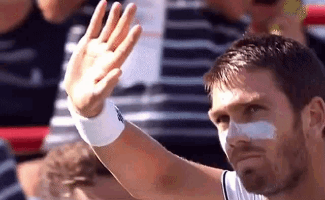 a man with a bandage on his nose is waving his hand .