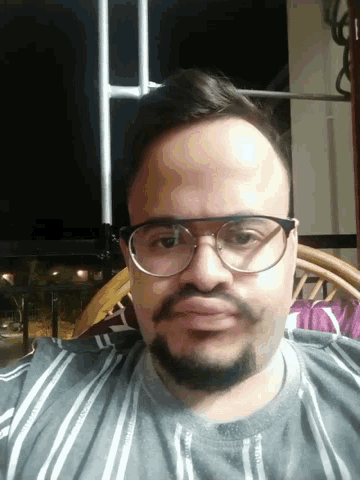 a man with glasses and a beard is wearing a striped shirt with the letter y on it
