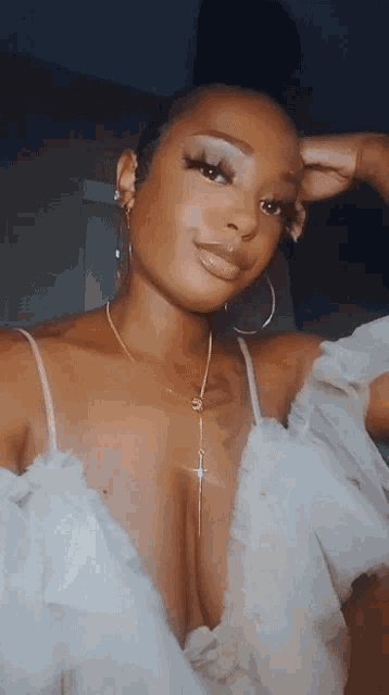 a woman wearing a white top and hoop earrings