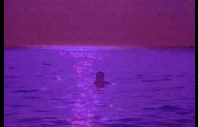 a person is swimming in a purple ocean