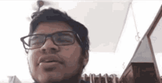 a man with glasses and a beard is making a funny face in a room .