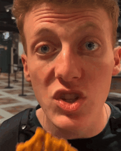 a close up of a man 's face while eating a piece of food