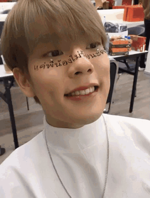 a young man with chinese writing on his face smiles for the camera