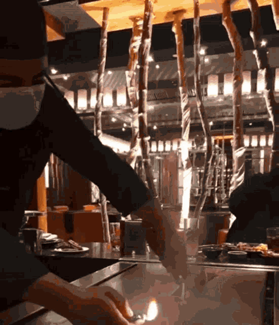 a person is lighting a candle in a restaurant at night