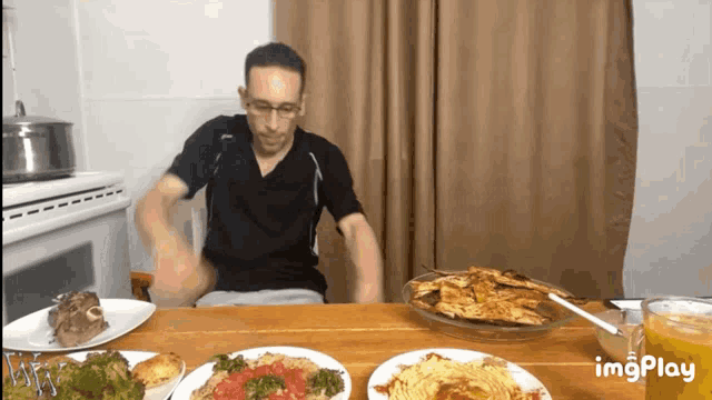 a man is sitting at a table with plates of food and a gif that says imgplay
