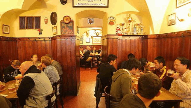 a group of people are sitting at tables in a restaurant with a sign above them that says ' brauerei '