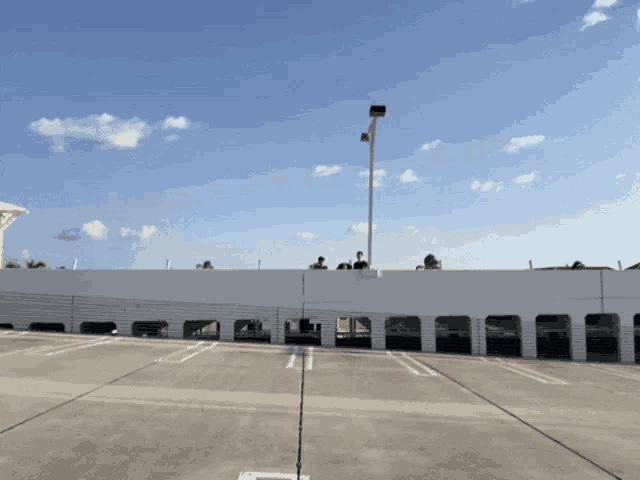 a group of people standing on top of a parking garage with a blue sky in the background