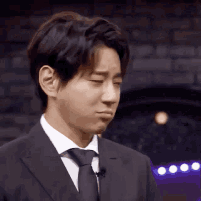 a man in a suit and tie is making a sad face with his eyes closed .