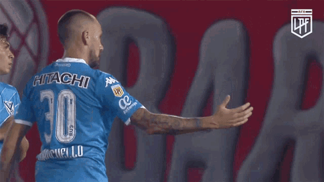 a soccer player wearing a blue hitachi jersey