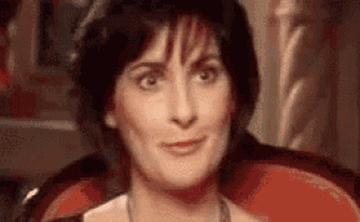 a close up of a woman sitting in a red chair making a funny face .