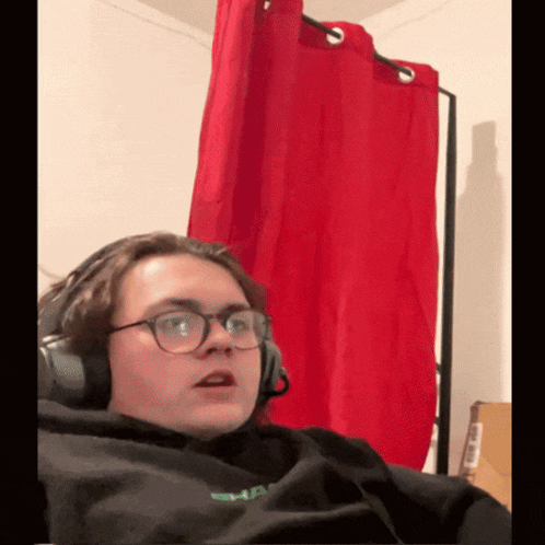 a person wearing headphones and a black sweatshirt with a green logo on the front