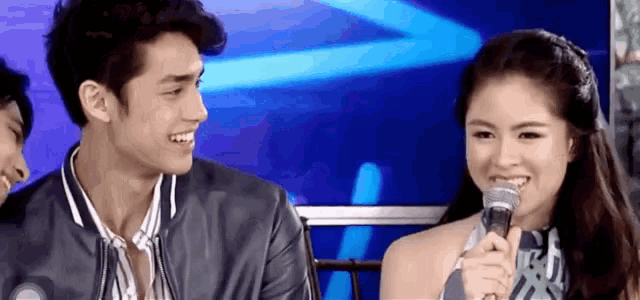 a man and a woman are sitting next to each other with a microphone .