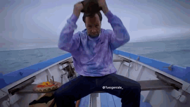 a man in a tie dye shirt sits on a boat