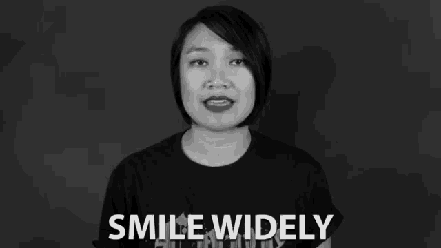 a woman in a black shirt says smile widely in a black and white photo