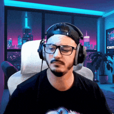 a man wearing headphones and glasses is sitting in front of a screen that says cam