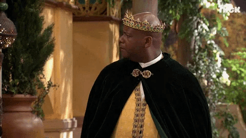 a man wearing a crown and a cape is standing in front of a sign that says nick