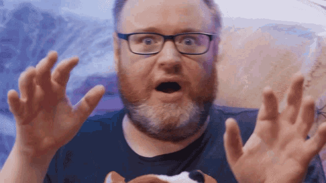 a man with glasses and a beard is making a shocked face