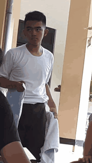 a young man in a white shirt holds a towel