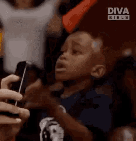 a young boy is crying while holding a cell phone in a crowd .