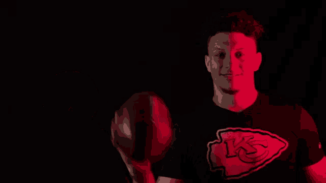 a man is holding a football in his hand in the dark .