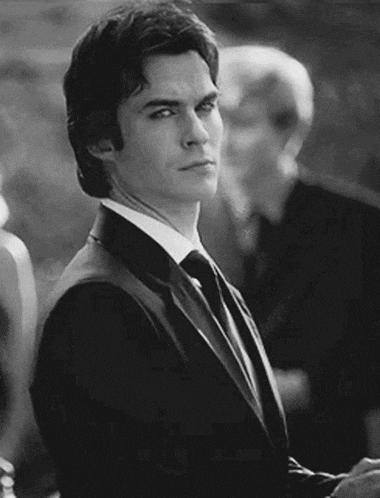 a man in a suit and tie stands in front of a group of people
