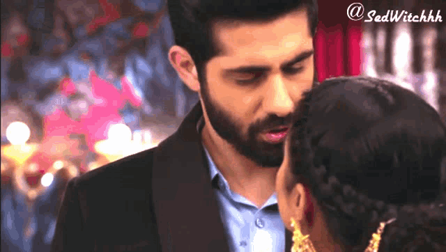 a man in a suit kisses a woman in a braided hairdo